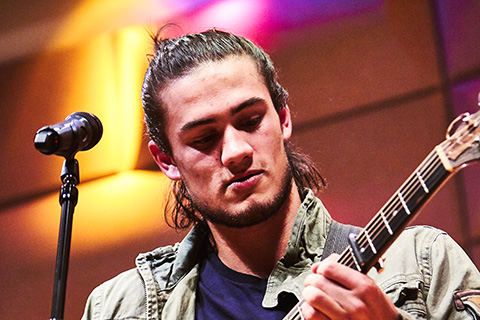 Man playing the guitar behind a microphone on stage